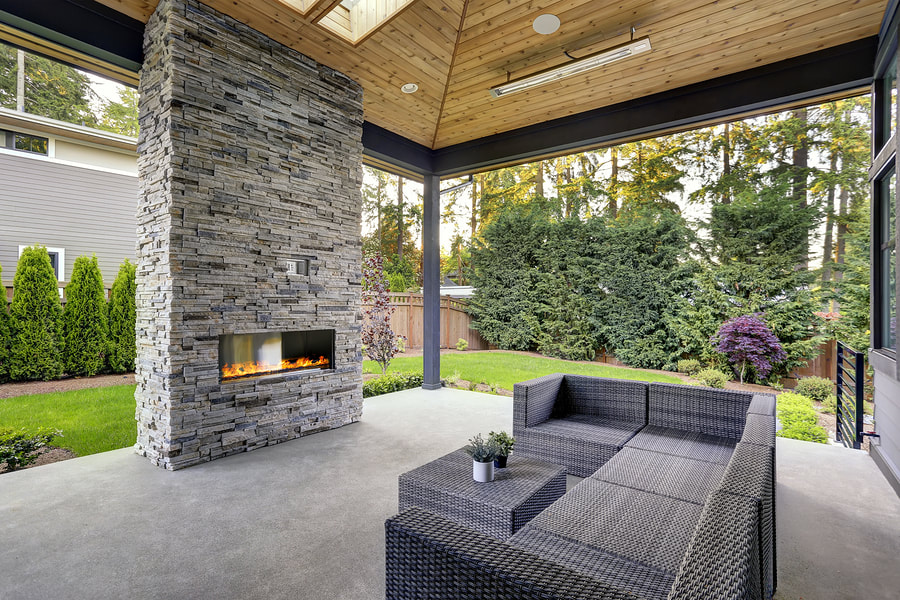 beautiful outdoor concrete patio with a stone fireplace and outdoor living area