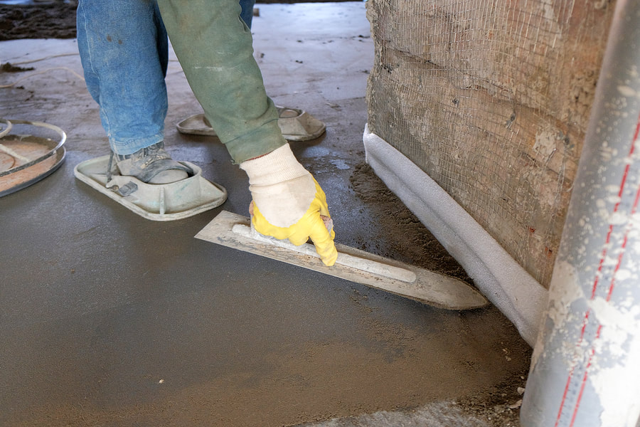 concrete contractor walking on set concrete while smoothing out joints along a wall